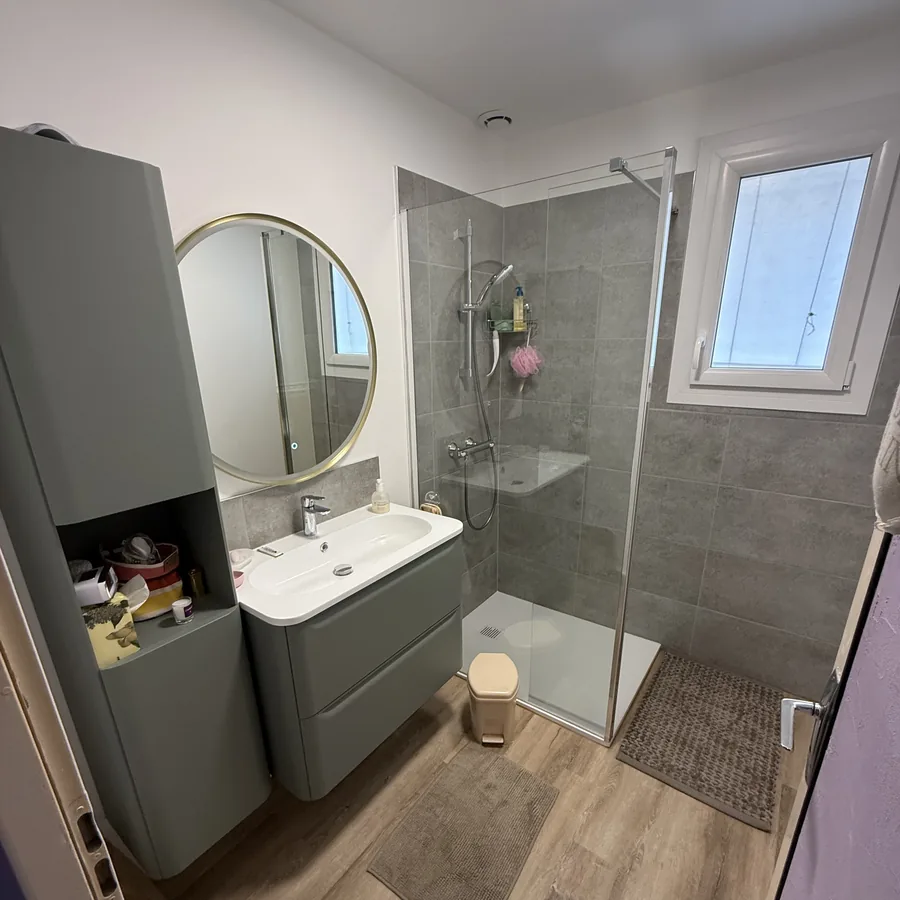 Salle de bains après rénovation : douche, meuble suspendu et sol imitation bois